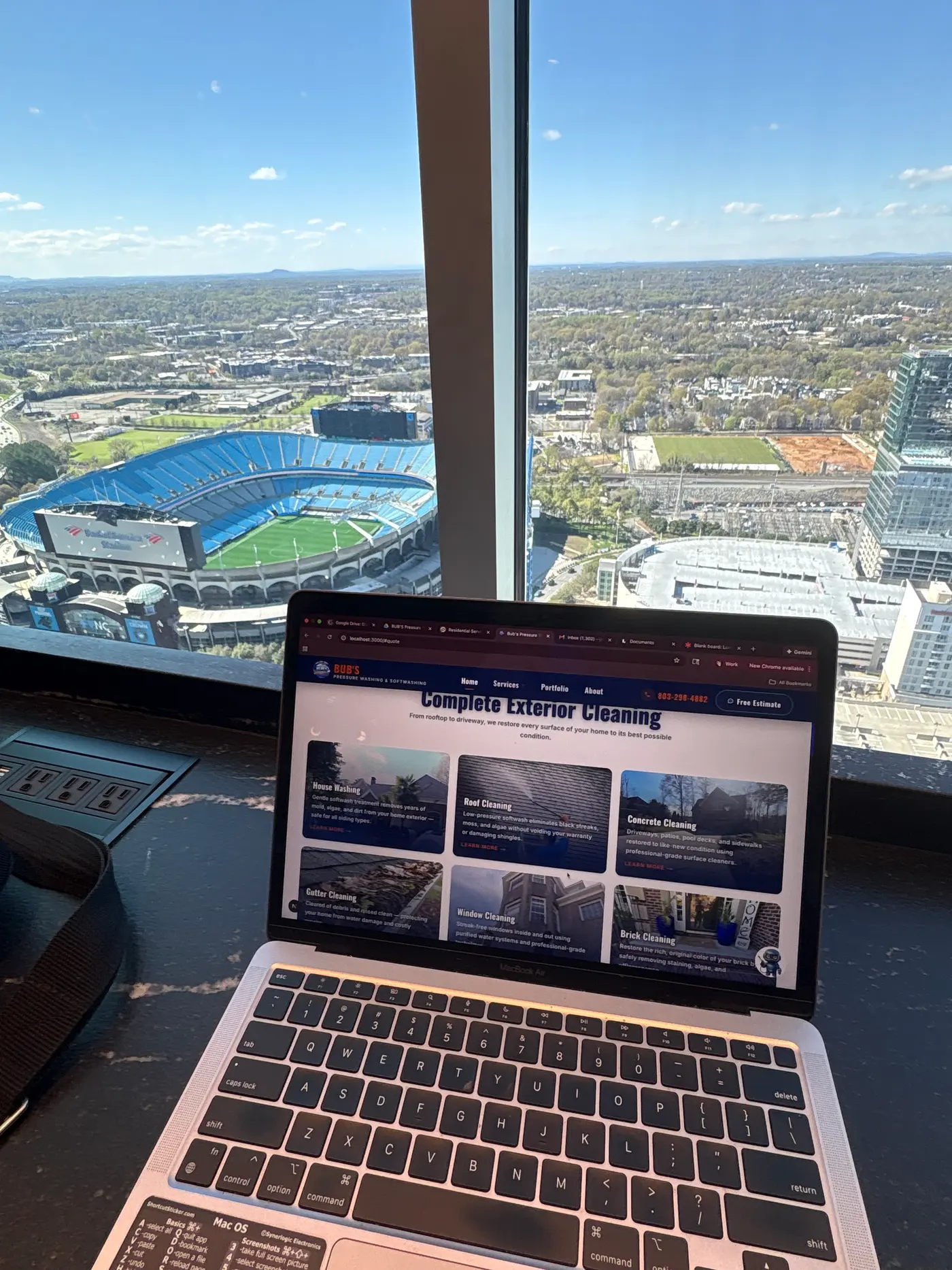 The New World Agency working from Uptown Charlotte, North Carolina overlooking Bank of America Stadium, with a client's website open on screen